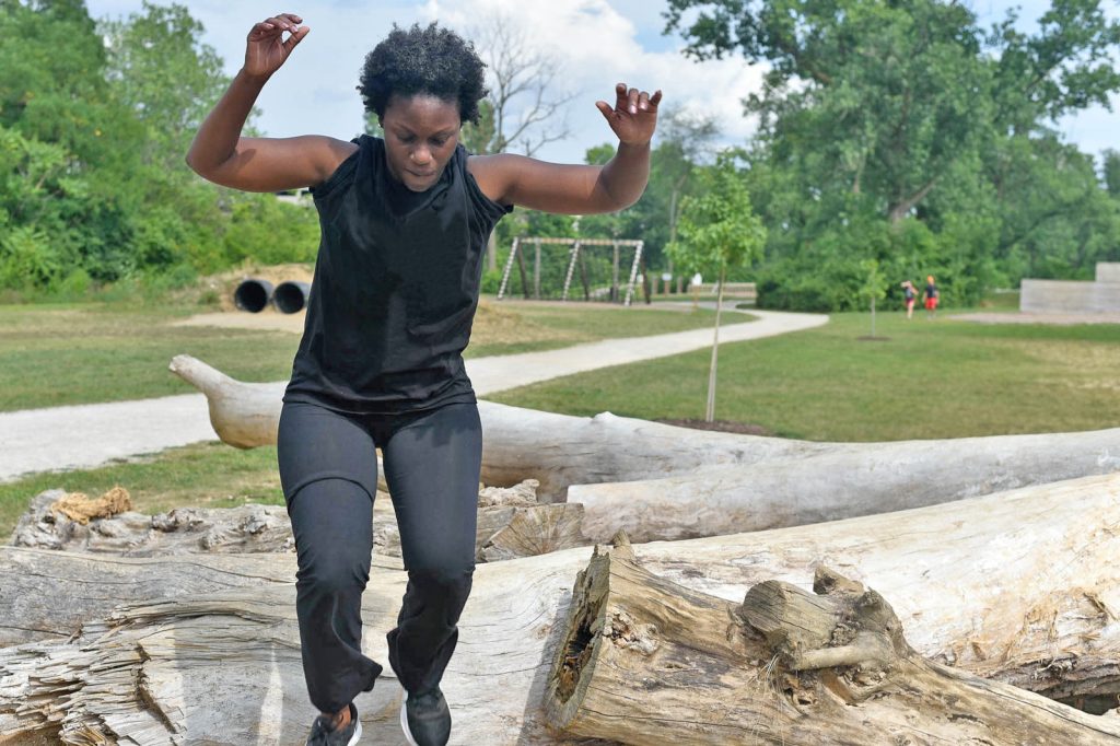 Woman on the log run on the obstacle course at Scioto Audubon Woman on the log run on the obstacle course at Scioto Audubon
